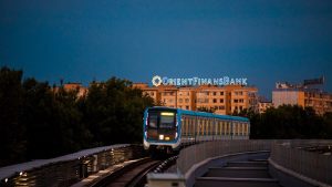 A modern train on railway tracks captured during evening in Tashkent, Uzbekistan with a cityscape backdrop.